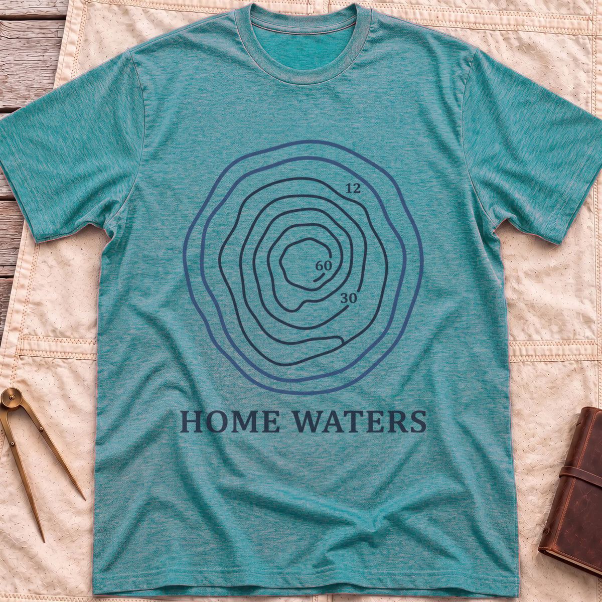 Front view of the heather galapagos blue Home Waters T-Shirt with a set of wavy contour lines marked 12, 30 and 60.
