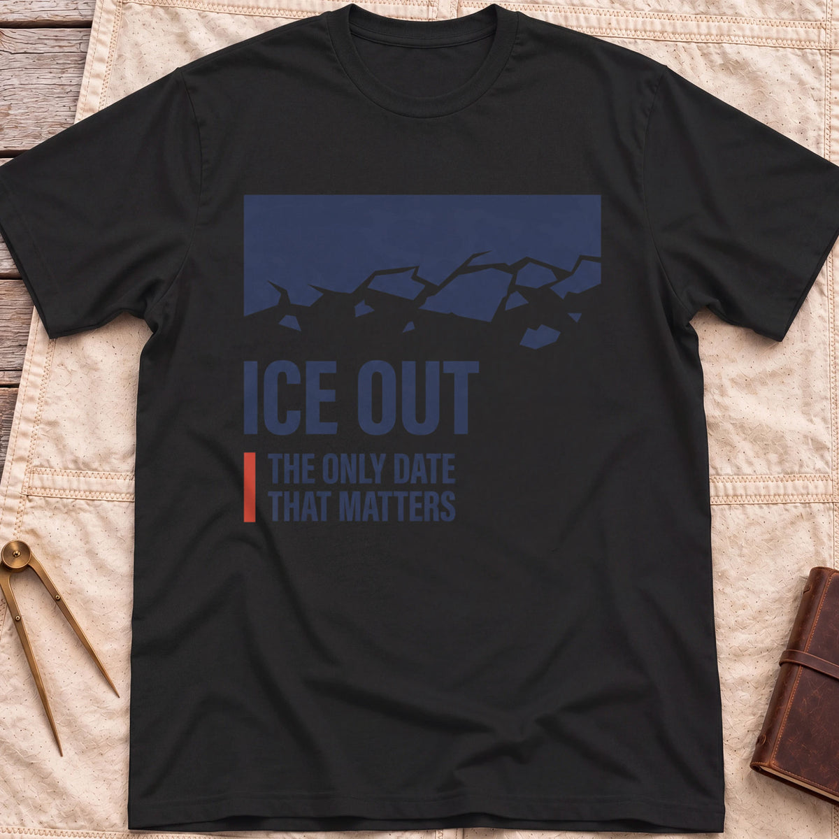 Front view of the black Ice Out T-Shirt with a navy block breaking into ice fragments above the words The Only Date That Matters.