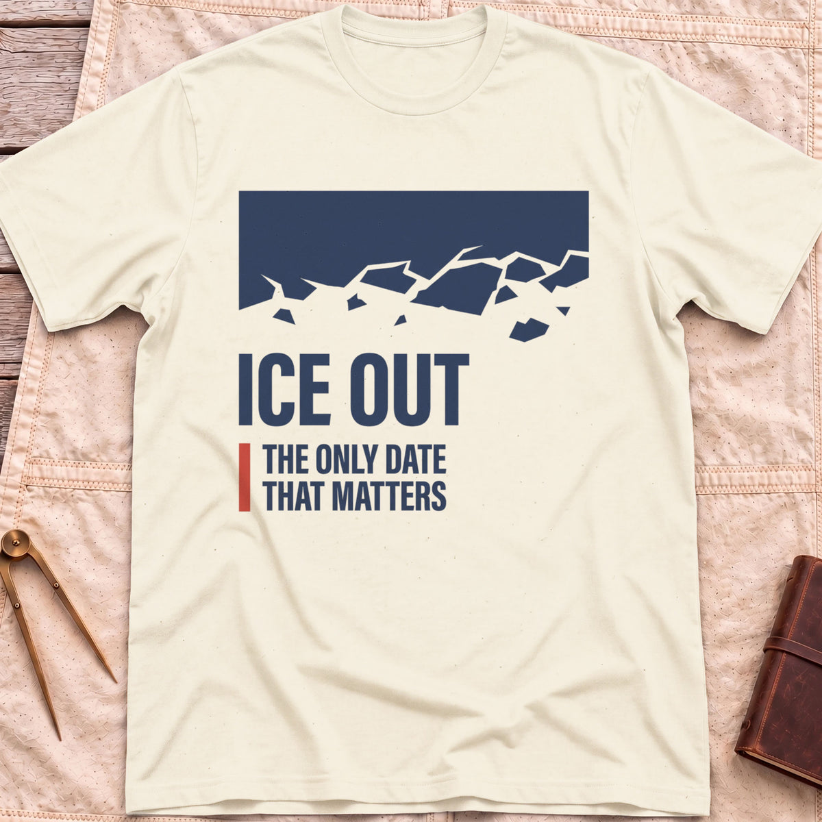 Front view of the natural Ice Out T-Shirt with a navy block breaking into ice fragments above the words The Only Date That Matters.