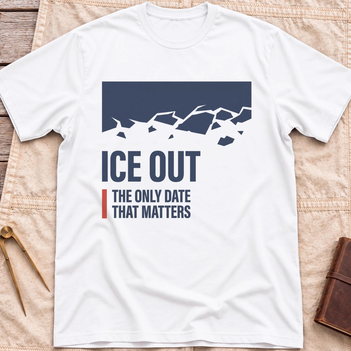Front view of the white Ice Out T-Shirt with a navy block breaking into ice fragments above the words The Only Date That Matters.