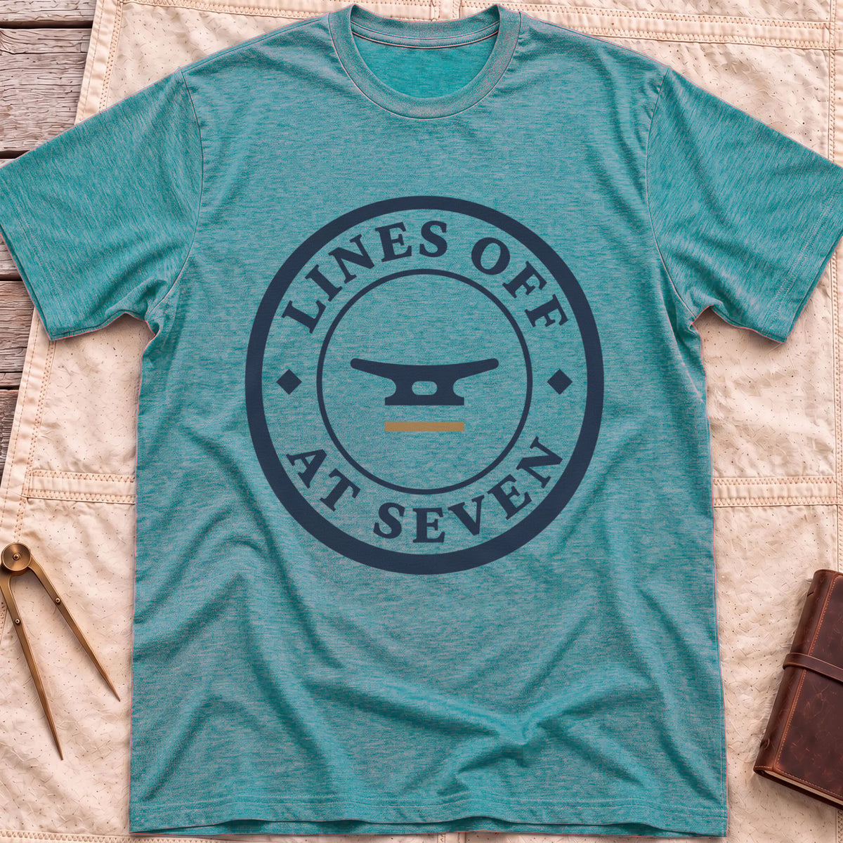 Front view of the heather galapagos blue Lines Off at Seven T-Shirt with a round badge showing a dock cleat, ringed by the words Lines Off at Seven.