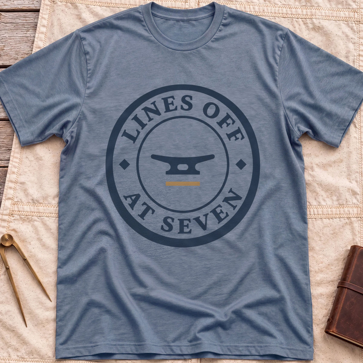 Front view of the heather indigo Lines Off at Seven T-Shirt with a round badge showing a dock cleat, ringed by the words Lines Off at Seven.