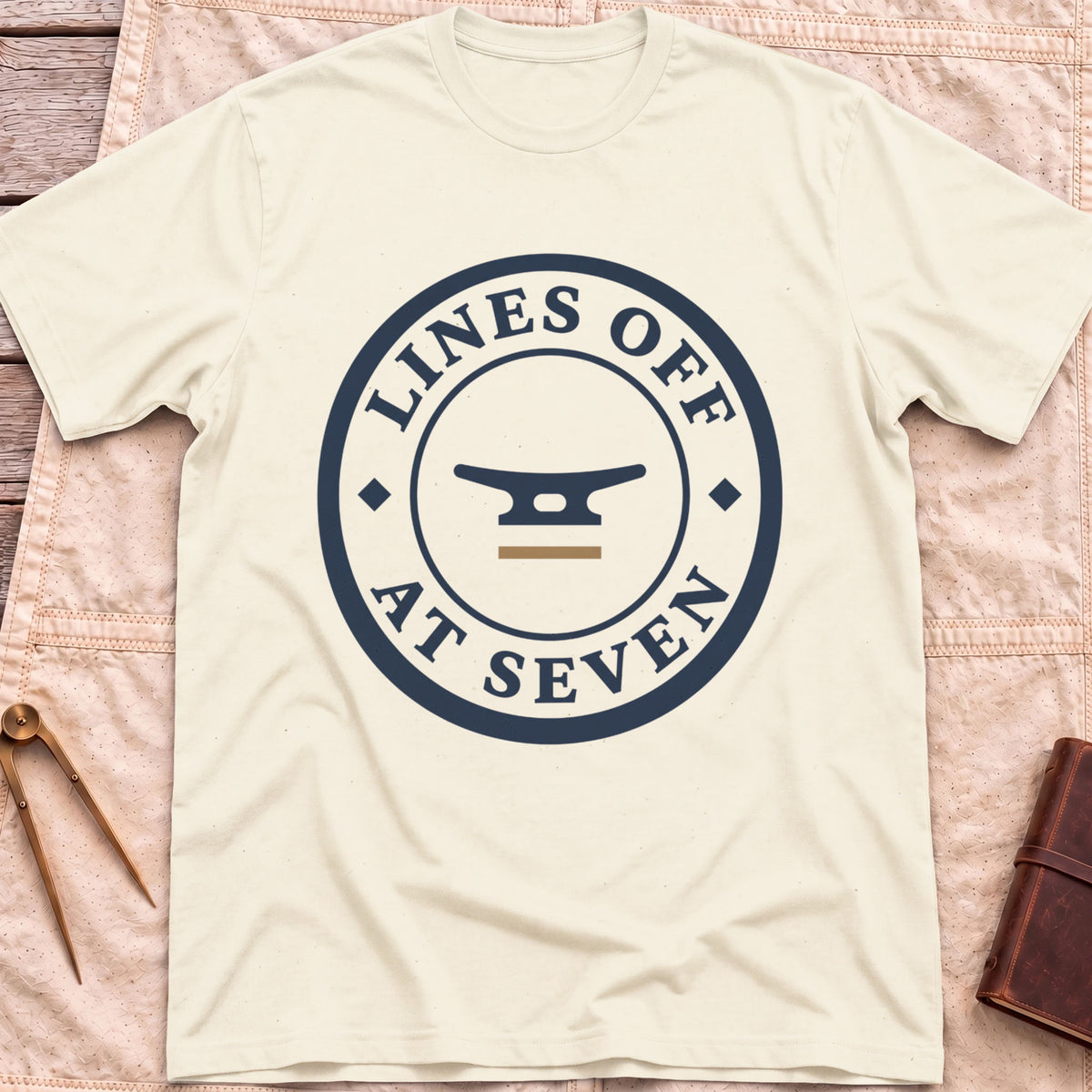 Front view of the natural Lines Off at Seven T-Shirt with a round badge showing a dock cleat, ringed by the words Lines Off at Seven.