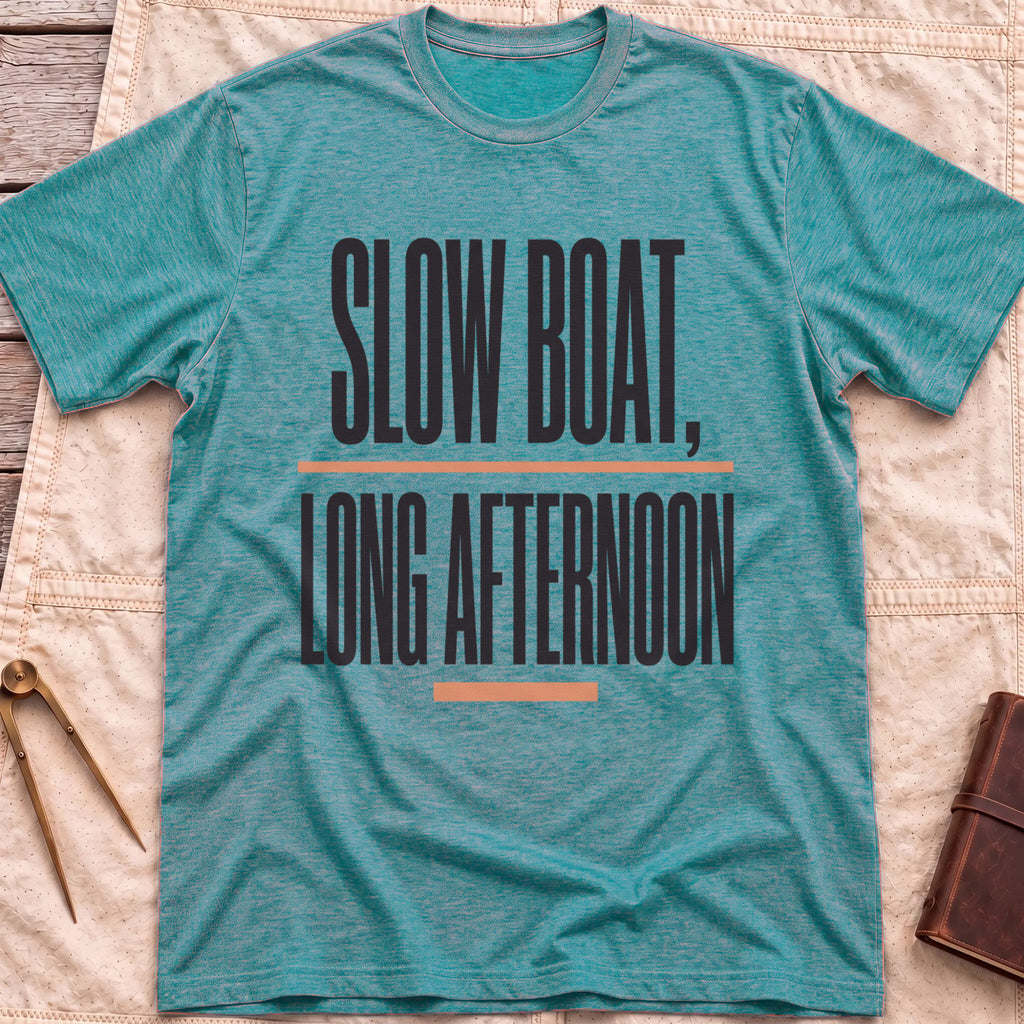Front view of the heather galapagos blue Long Afternoon T-Shirt with the words Slow Boat, Long Afternoon in tall condensed capitals between coral rules.