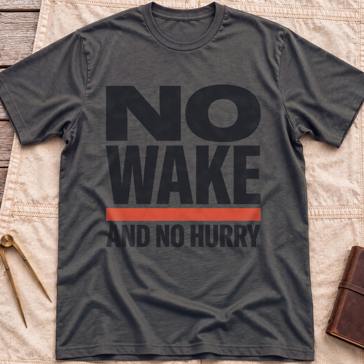 Front view of the dark heather No Wake T-Shirt with the words No Wake in large bold letters over a red bar and the line And No Hurry.