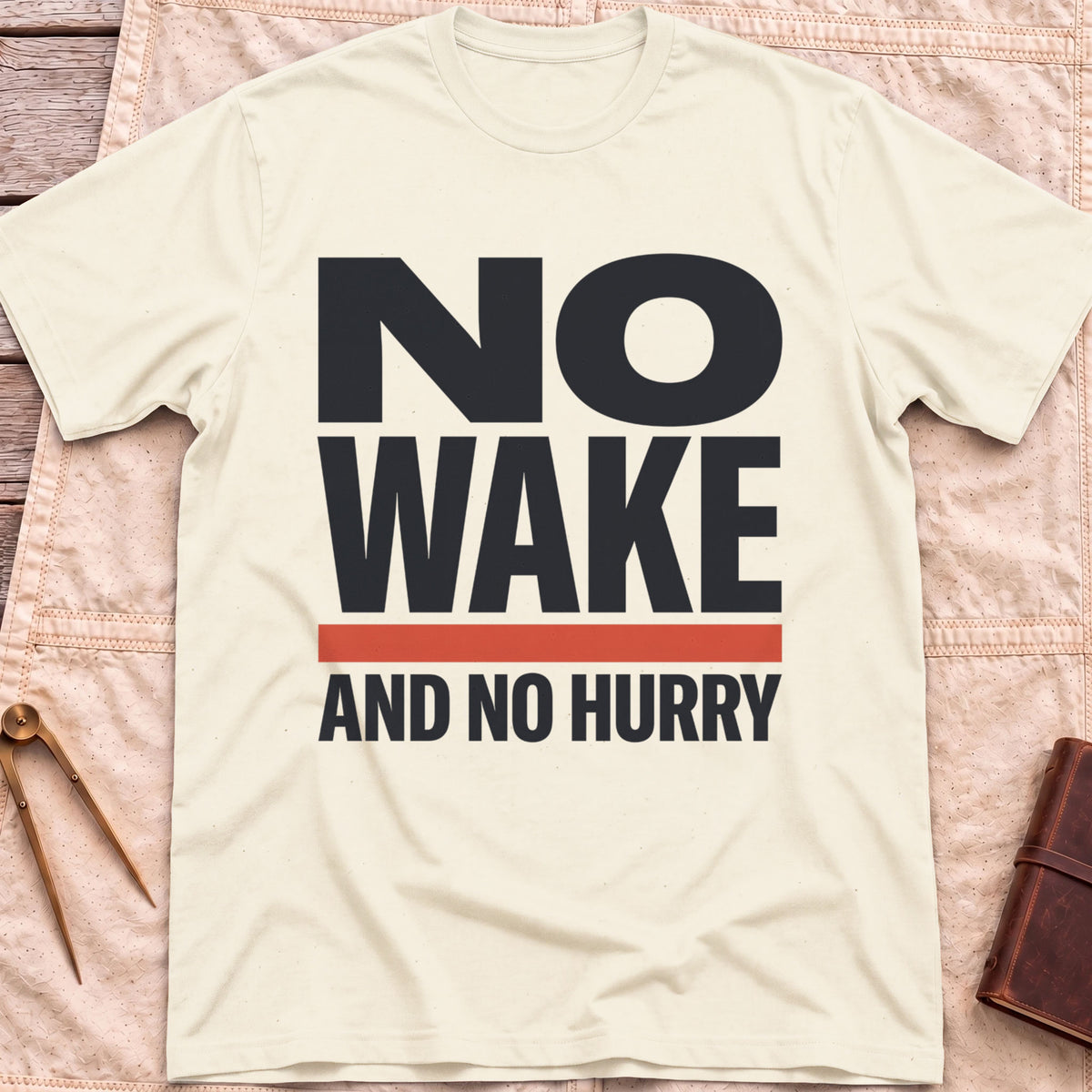 Front view of the natural No Wake T-Shirt with the words No Wake in large bold letters over a red bar and the line And No Hurry.