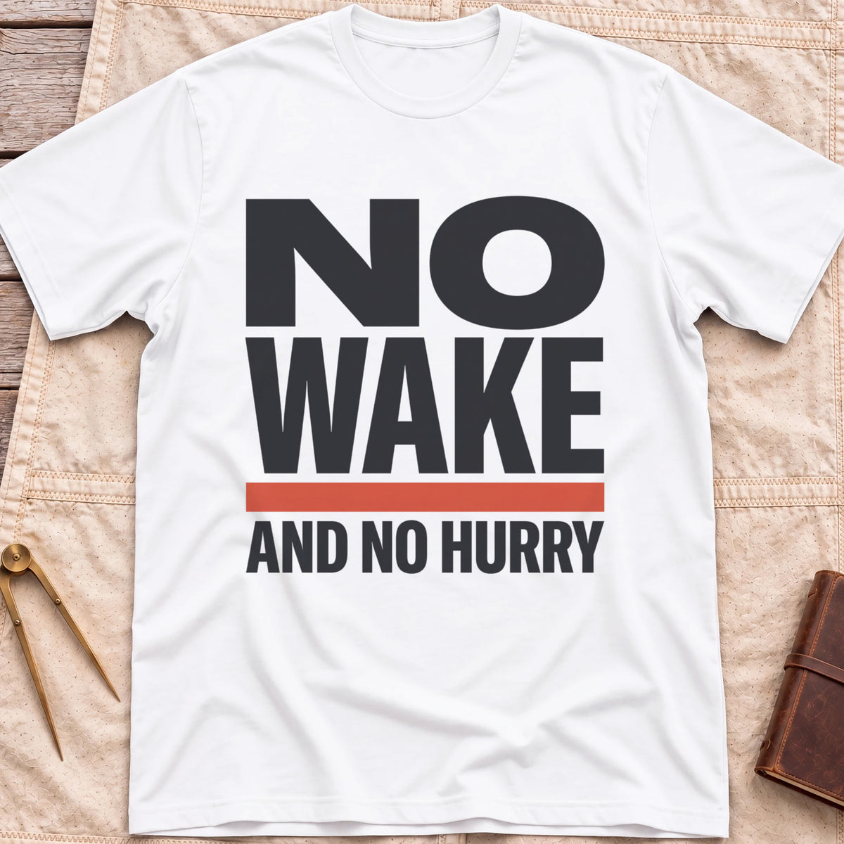 Front view of the white No Wake T-Shirt with the words No Wake in large bold letters over a red bar and the line And No Hurry.