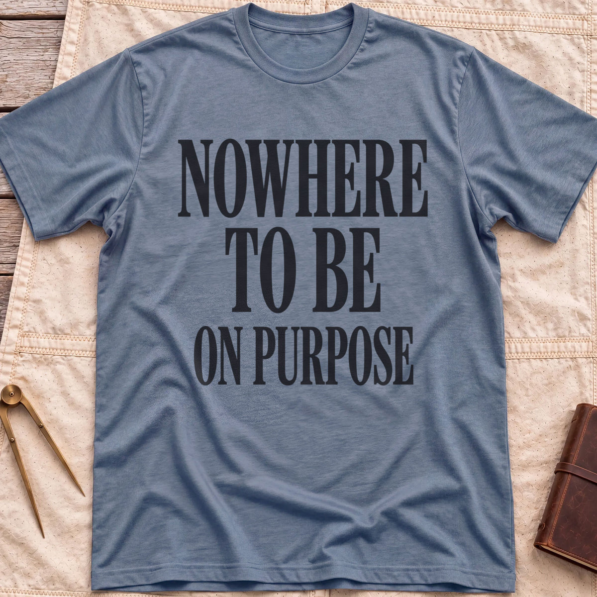 Front view of the heather indigo Nowhere to Be T-Shirt with the words Nowhere to Be, On Purpose in tall condensed capitals.
