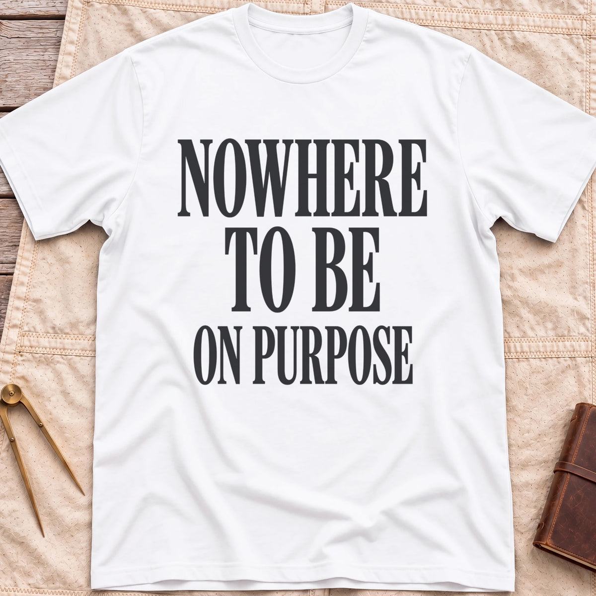 Front view of the white Nowhere to Be T-Shirt with the words Nowhere to Be, On Purpose in tall condensed capitals.