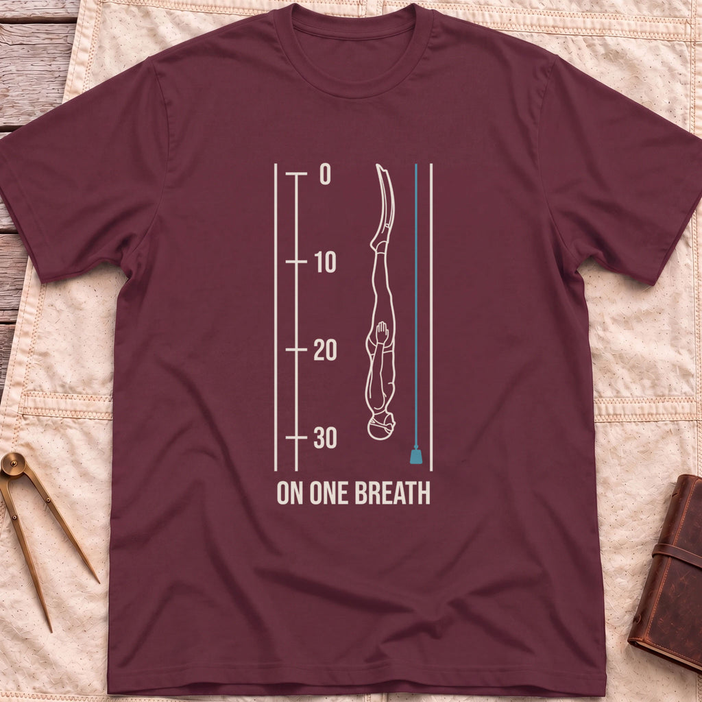 Front view of the maroon On One Breath T-Shirt with a diver descending headfirst beside a depth scale from 0 to 30, above the words On One Breath.