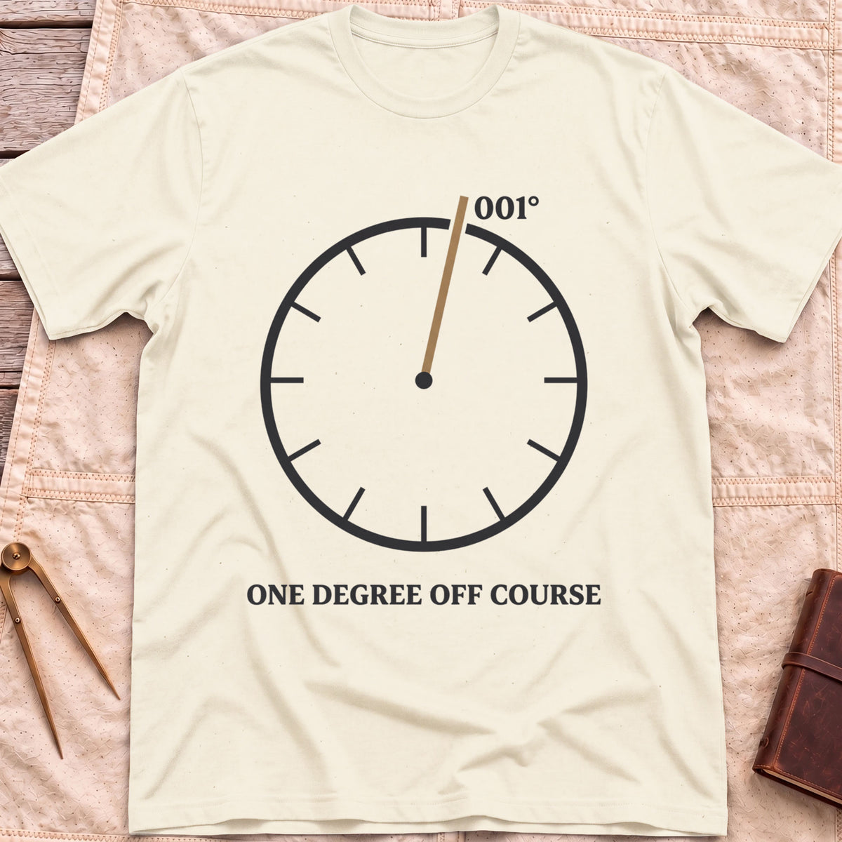 Front view of the natural One Degree Off Course T-Shirt with a round dial and a tan needle pointing to 001°.