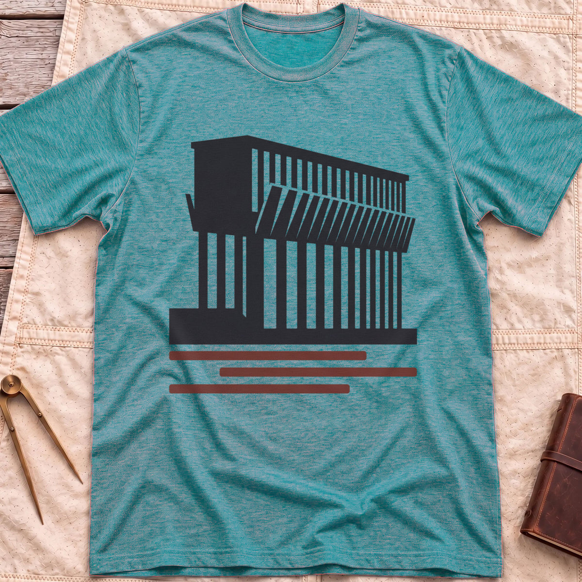 Front view of the heather galapagos blue Ore Dock T-Shirt with a silhouette of an ore dock with a row of angled chutes above red lines.