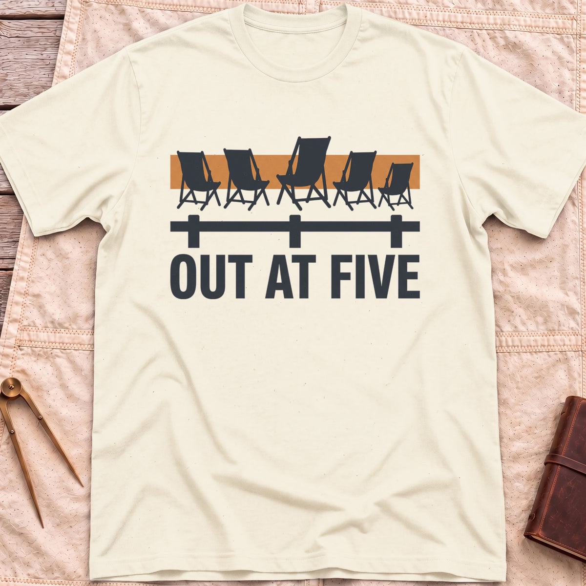 Front view of the natural Out at Five T-Shirt with a row of folding chairs along a dock rail against an orange band, above the words Out at Five.