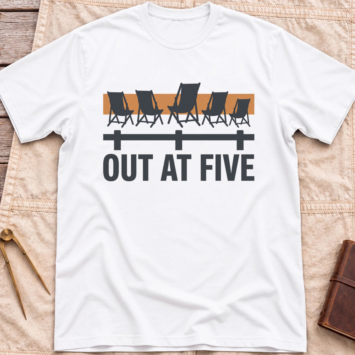 Front view of the white Out at Five T-Shirt with a row of folding chairs along a dock rail against an orange band, above the words Out at Five.