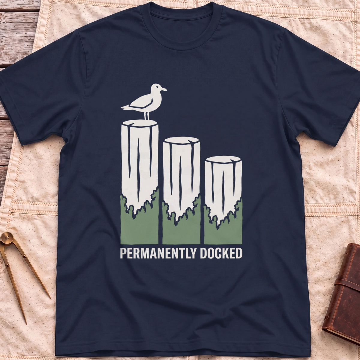 Front view of the navy Permanently Docked T-Shirt with a seagull perched on three wooden pilings.