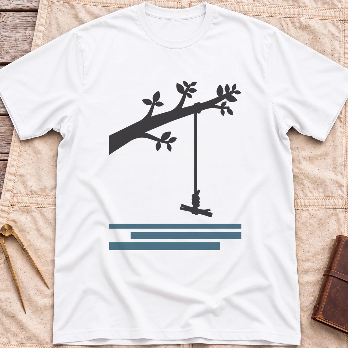 Front view of the white Rope Swing T-Shirt with a rope swing hanging from a leafy branch above water lines.