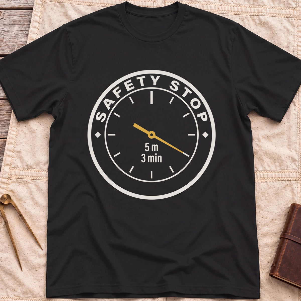 Front view of the black Safety Stop T-Shirt with a round gauge reading Safety Stop around the edge and 5 m, 3 min at the centre.