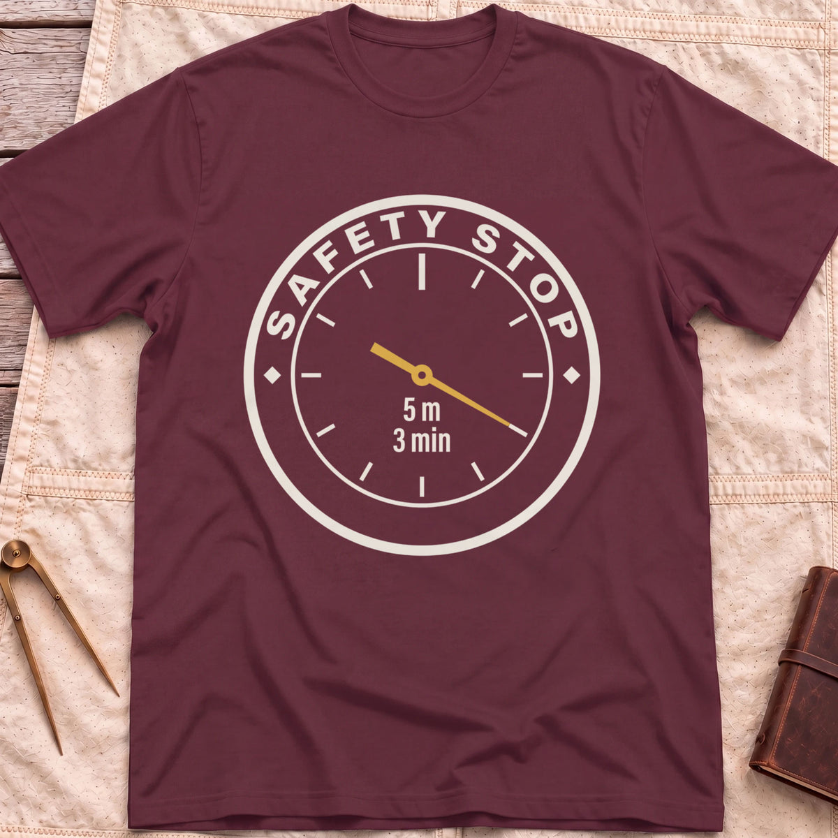 Front view of the maroon Safety Stop T-Shirt with a round gauge reading Safety Stop around the edge and 5 m, 3 min at the centre.