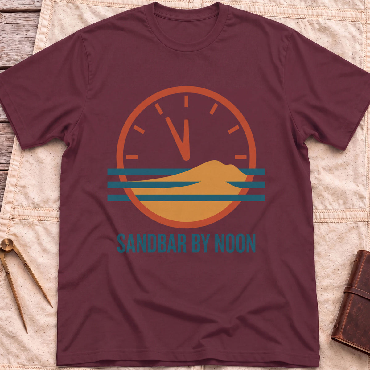 Front view of the maroon Sandbar by Noon T-Shirt with a clock face set just before twelve above a sandbar and water lines.
