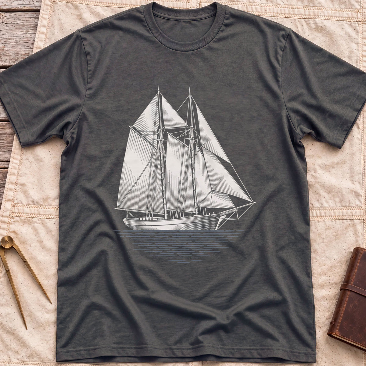 Front view of the dark heather Snug Harbour T-Shirt with a detailed white illustration of a two-masted sailing ship on the water.