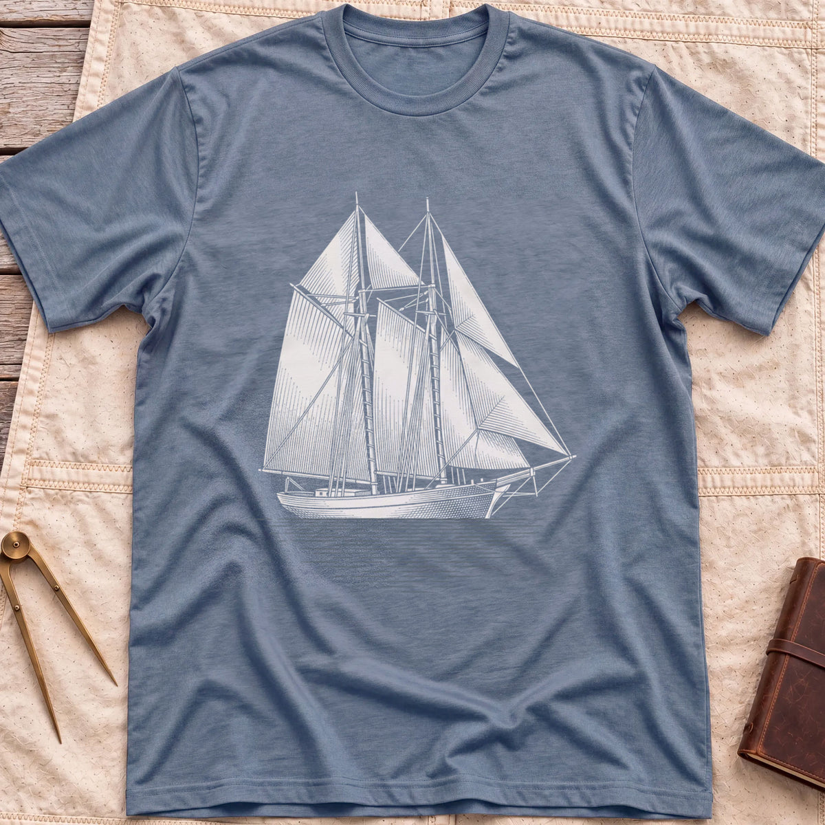 Front view of the heather indigo Snug Harbour T-Shirt with a detailed white illustration of a two-masted sailing ship on the water.