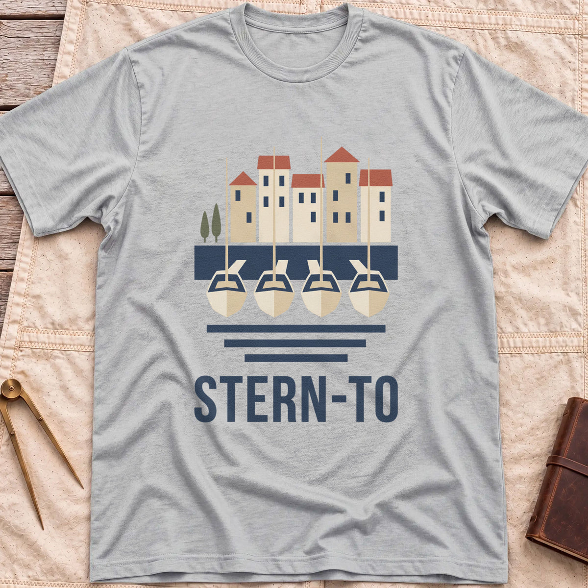 Front view of the sport grey Stern-To T-Shirt with four boats moored stern-first to a quay below a row of harbour houses, above the word Stern-To.