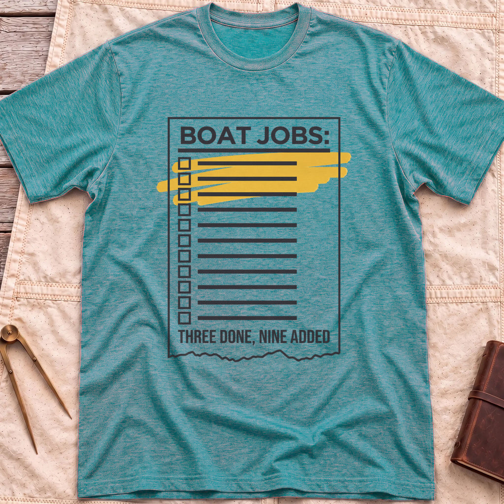 Front view of the heather galapagos blue Still on the List T-Shirt with a Boat Jobs checklist, its top items highlighted in yellow, above the words Three Done, Nine Added.