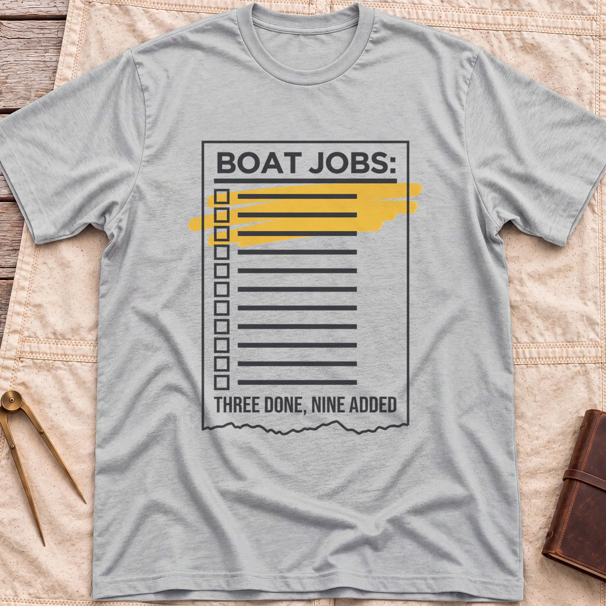 Front view of the sport grey Still on the List T-Shirt with a Boat Jobs checklist, its top items highlighted in yellow, above the words Three Done, Nine Added.