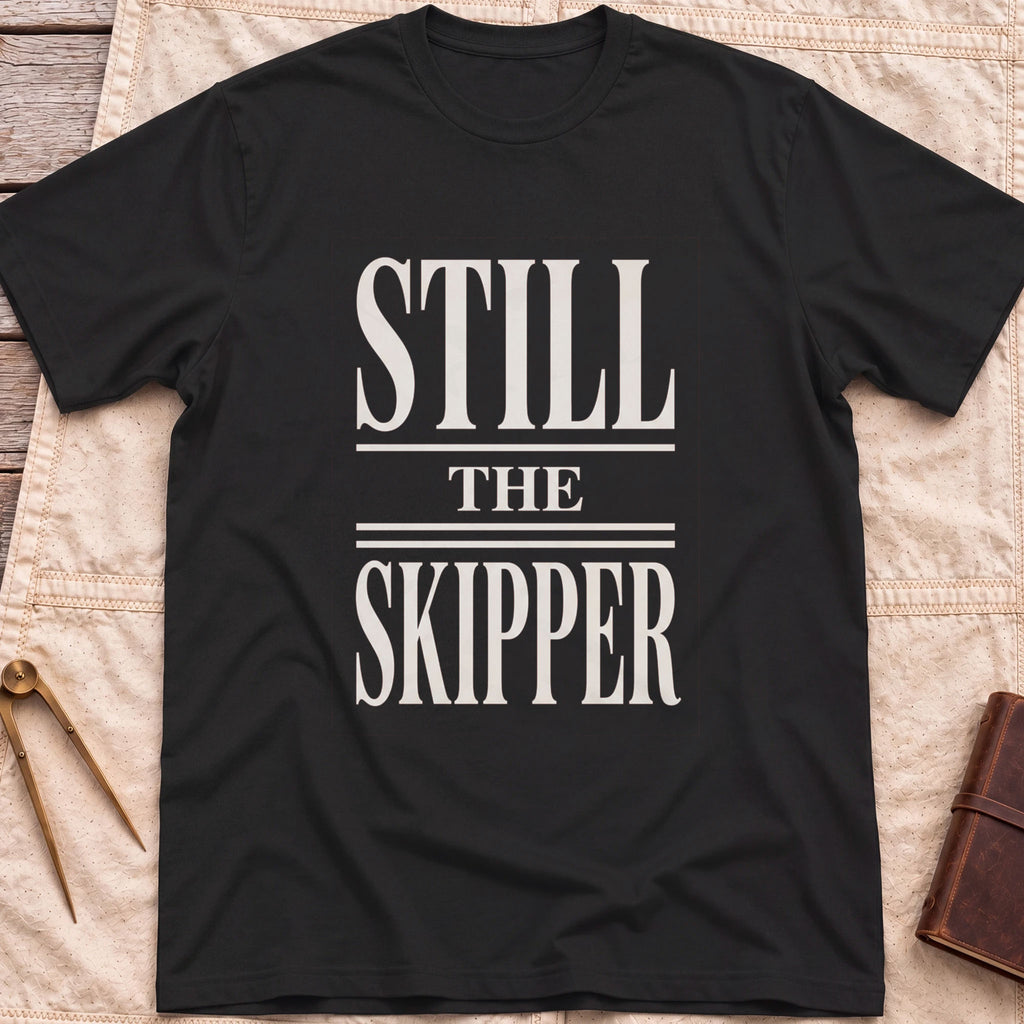 Front view of the black Still the Skipper T-Shirt with the words Still the Skipper in cream serif capitals.