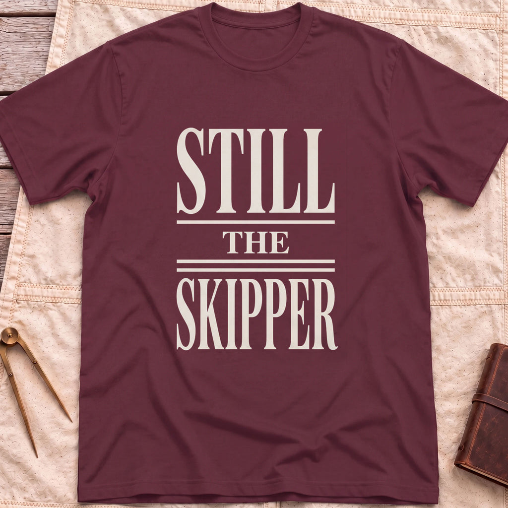 Front view of the maroon Still the Skipper T-Shirt with the words Still the Skipper in cream serif capitals.