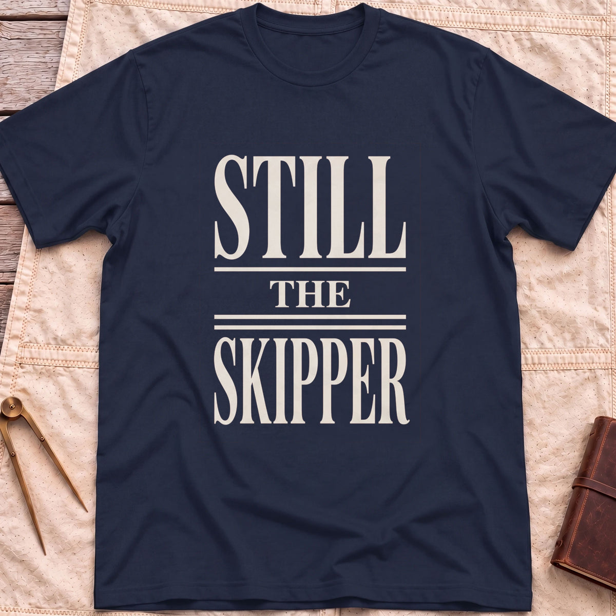 Front view of the navy Still the Skipper T-Shirt with the words Still the Skipper in cream serif capitals.