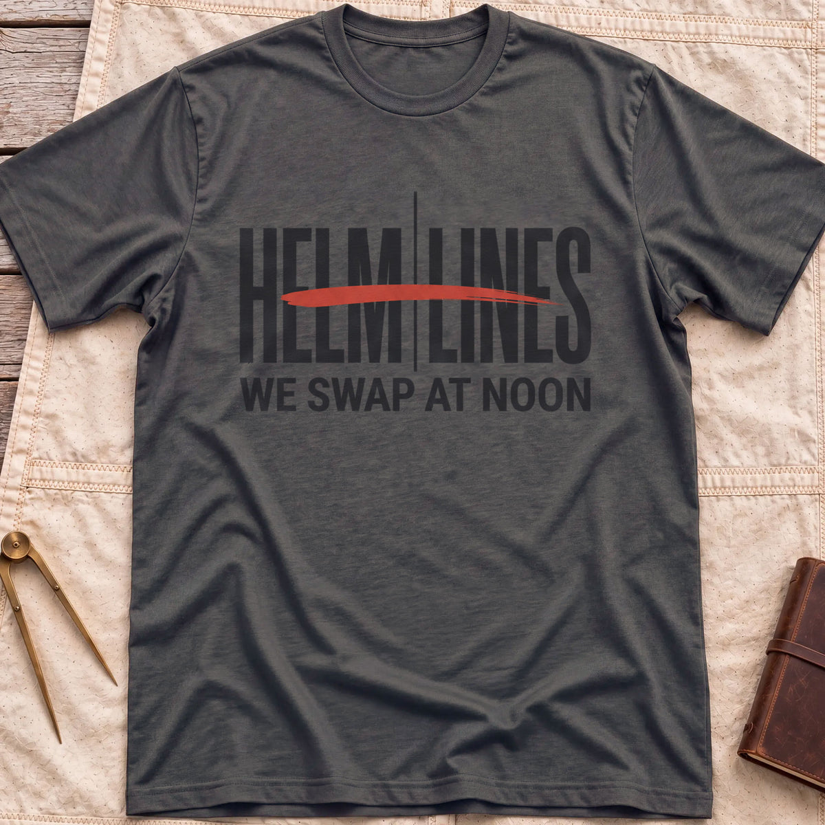 Front view of the dark heather Swap at Noon T-Shirt with the words Helm and Lines split by a vertical line and a red brushstroke, above We Swap at Noon.