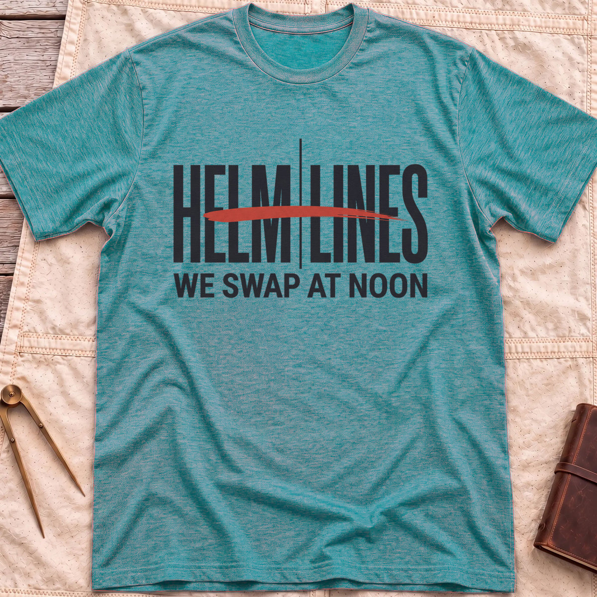 Front view of the heather galapagos blue Swap at Noon T-Shirt with the words Helm and Lines split by a vertical line and a red brushstroke, above We Swap at Noon.