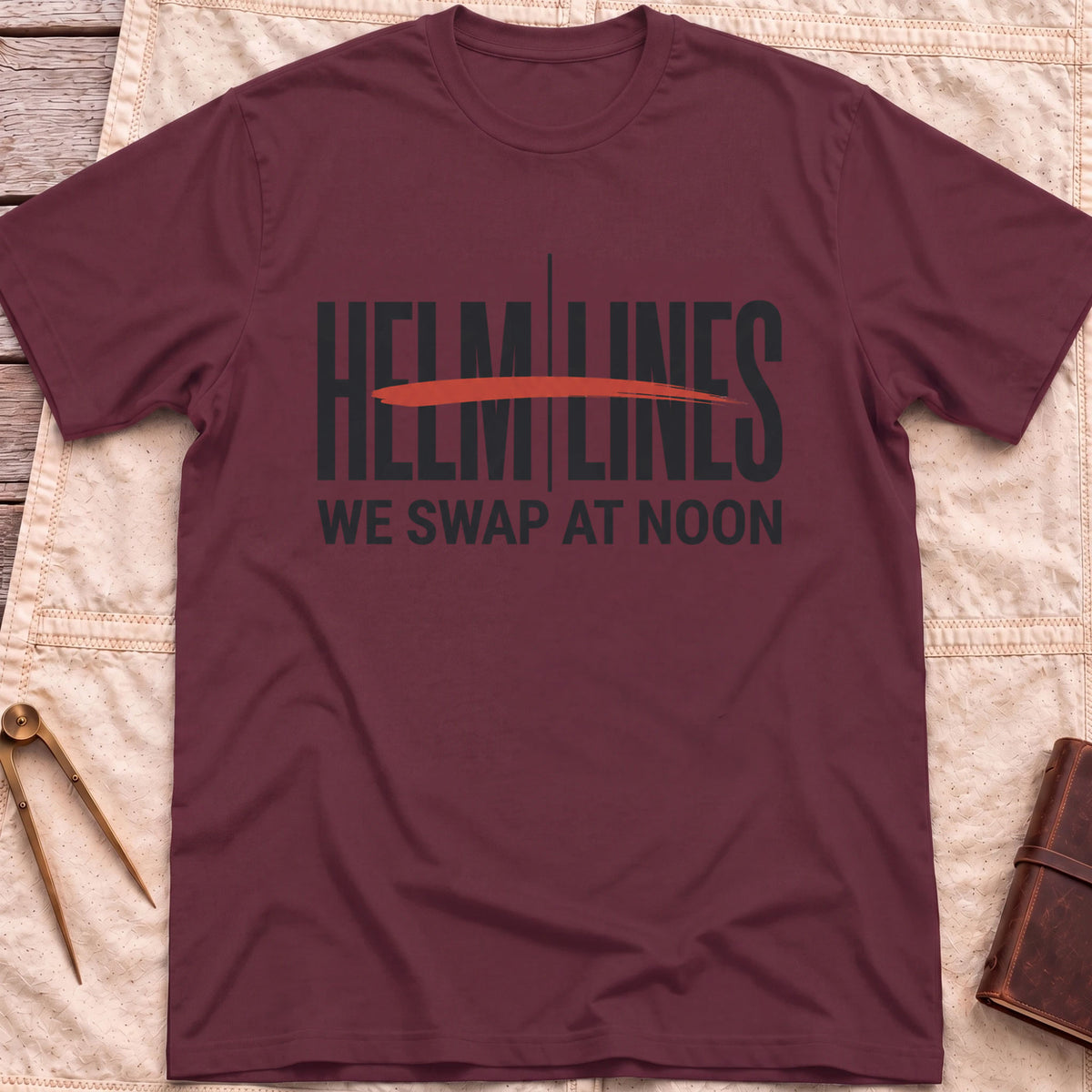 Front view of the maroon Swap at Noon T-Shirt with the words Helm and Lines split by a vertical line and a red brushstroke, above We Swap at Noon.
