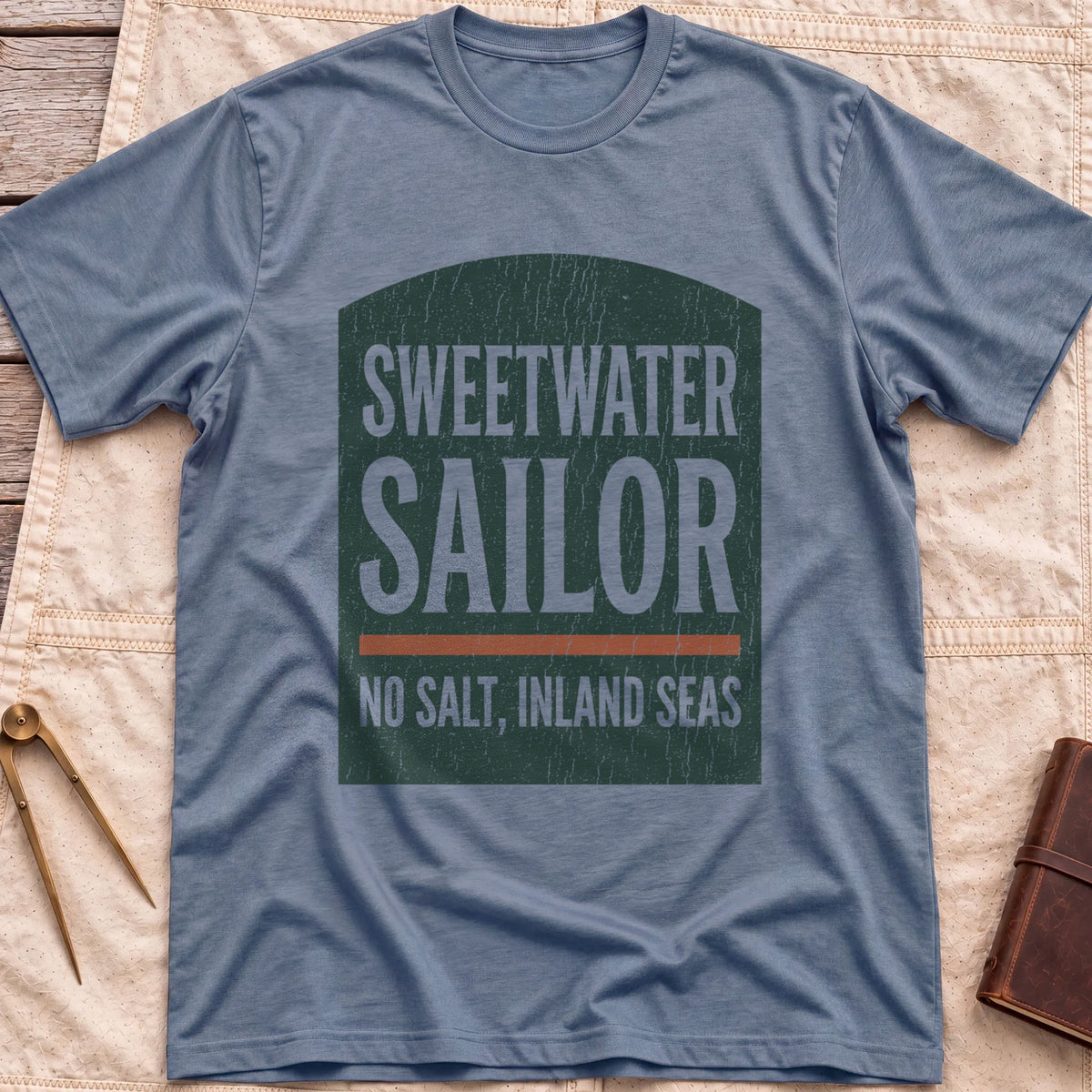 Front view of the heather indigo Sweetwater Sailor T-Shirt with an arched green panel reading Sweetwater Sailor above No Salt, Inland Seas.