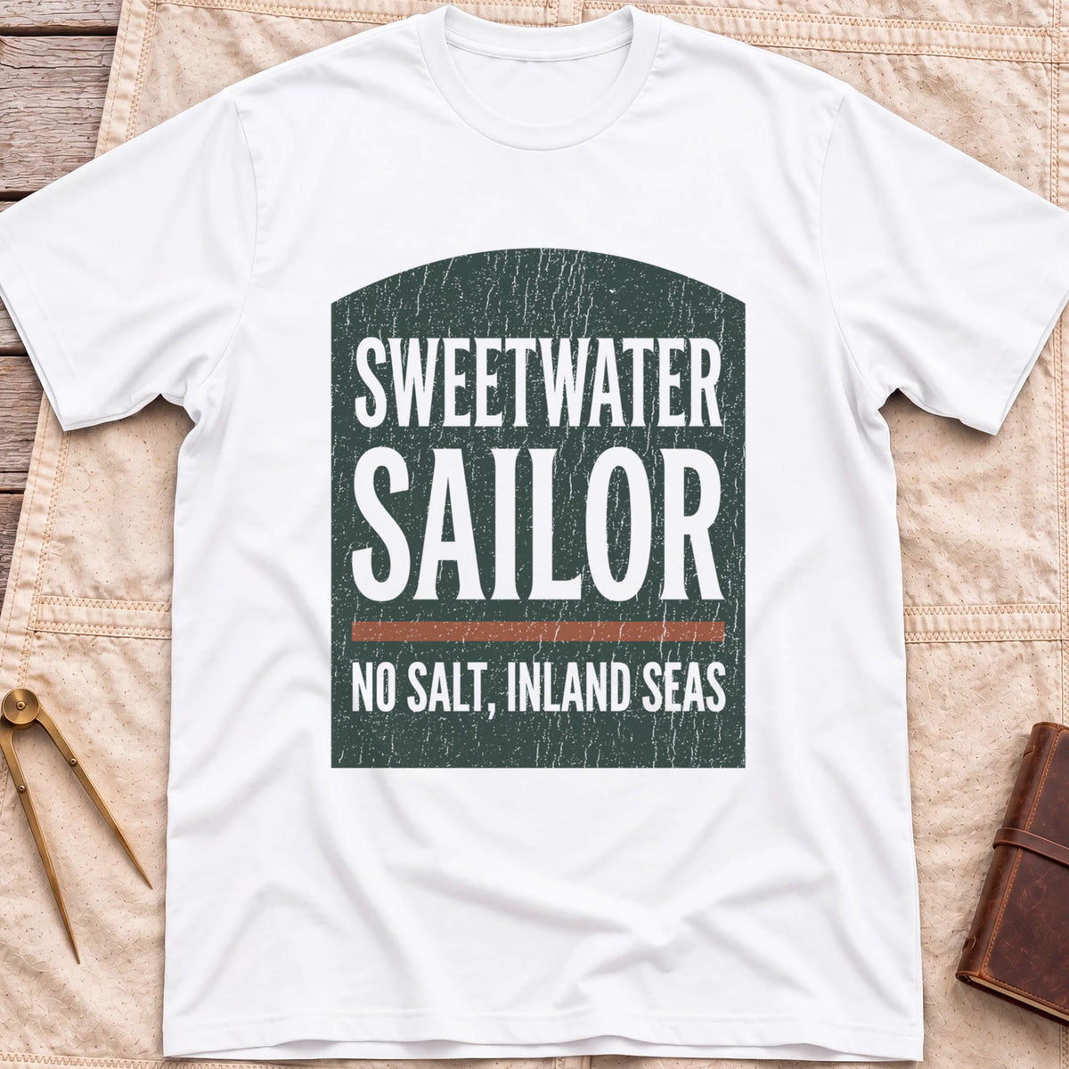 Front view of the white Sweetwater Sailor T-Shirt with an arched green panel reading Sweetwater Sailor above No Salt, Inland Seas.