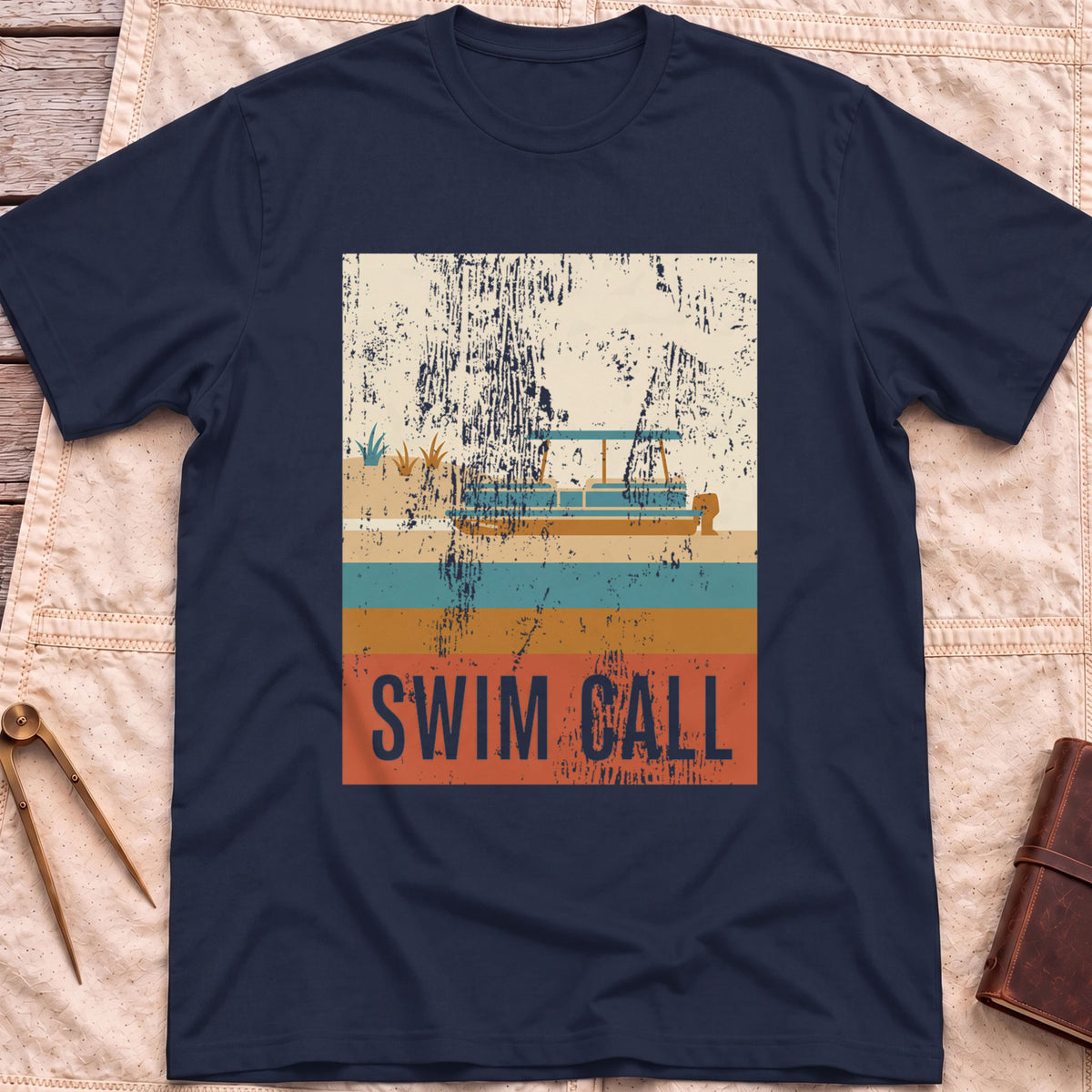Front view of the navy Swim Call T-Shirt with a distressed retro poster of a canopied pontoon boat over striped water above the words Swim Call.