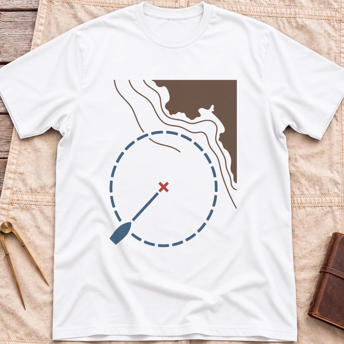 Front view of the white Swing Circle T-Shirt with a boat on a line inside a dashed circle around a red cross, beside a stretch of coastline.