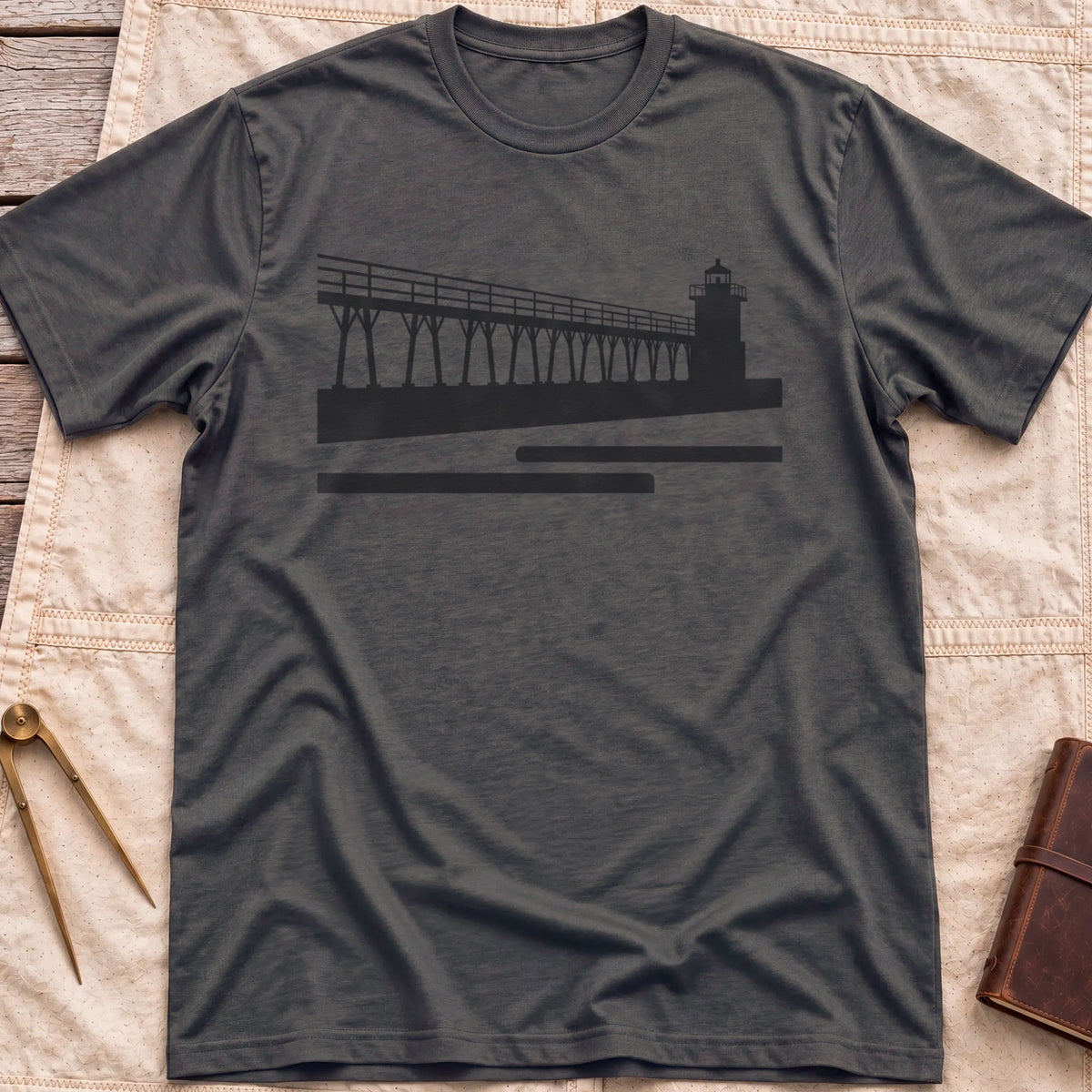 Front view of the dark heather The Catwalk T-Shirt with a silhouette of a raised walkway running along a pier to a lighthouse.