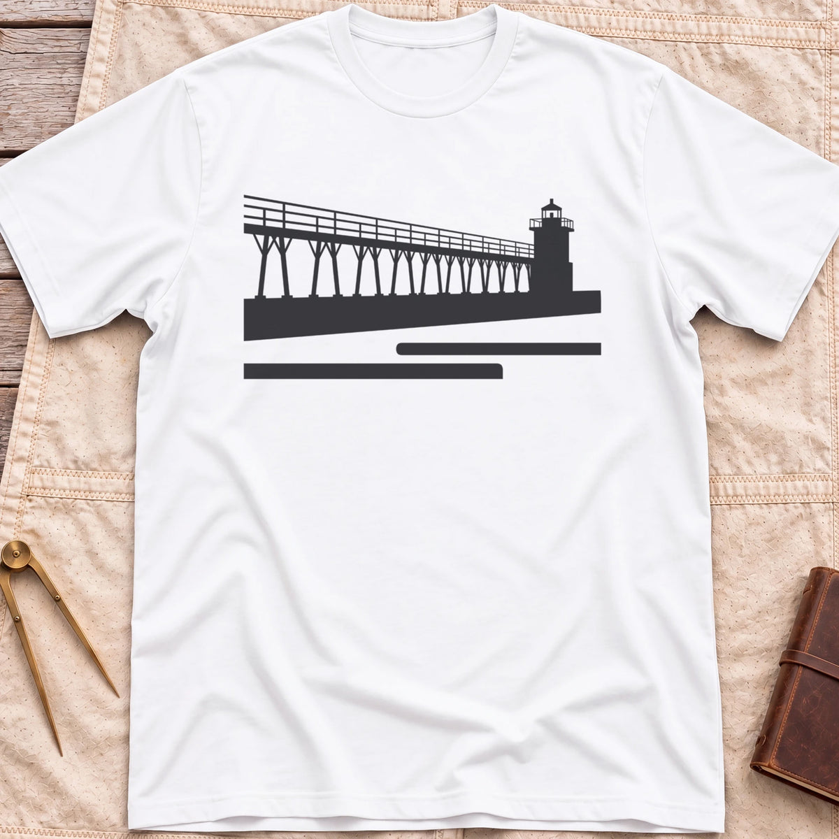 Front view of the white The Catwalk T-Shirt with a silhouette of a raised walkway running along a pier to a lighthouse.