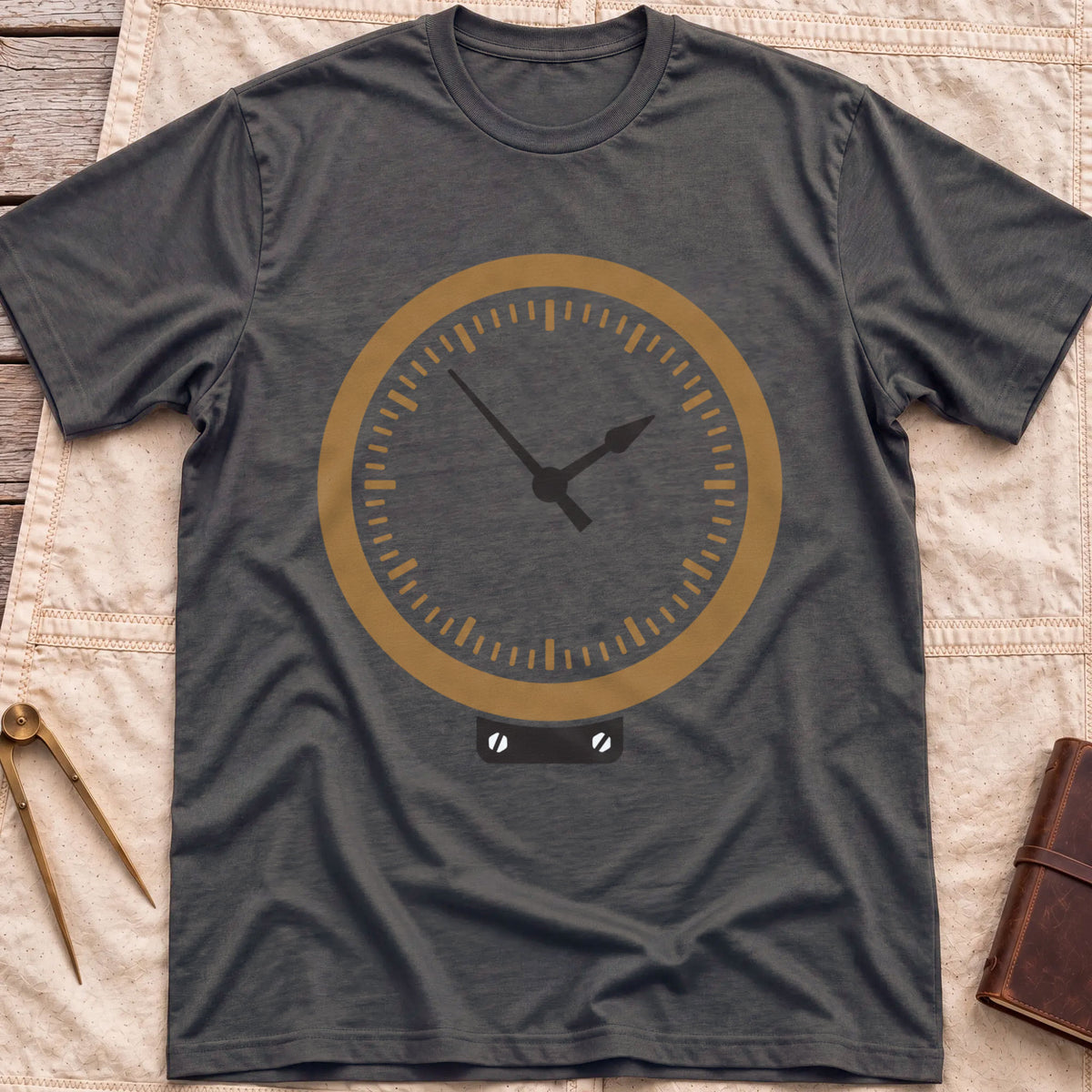 Front view of the dark heather The Glass T-Shirt with a round brass-rimmed dial and two hands on a small mounting plate.