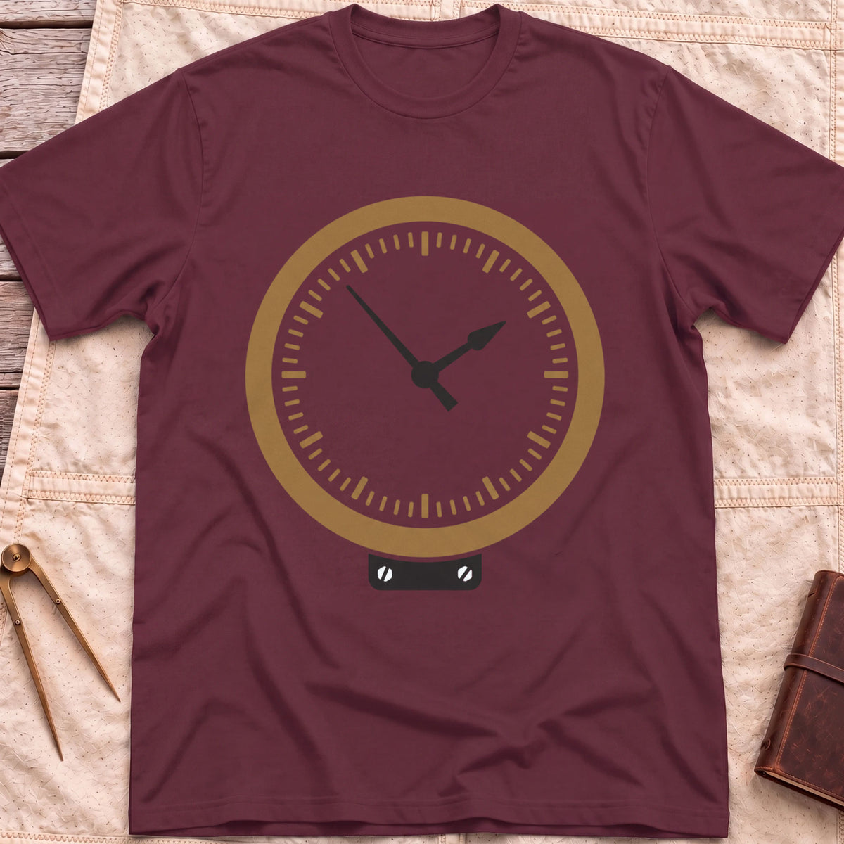 Front view of the maroon The Glass T-Shirt with a round brass-rimmed dial and two hands on a small mounting plate.