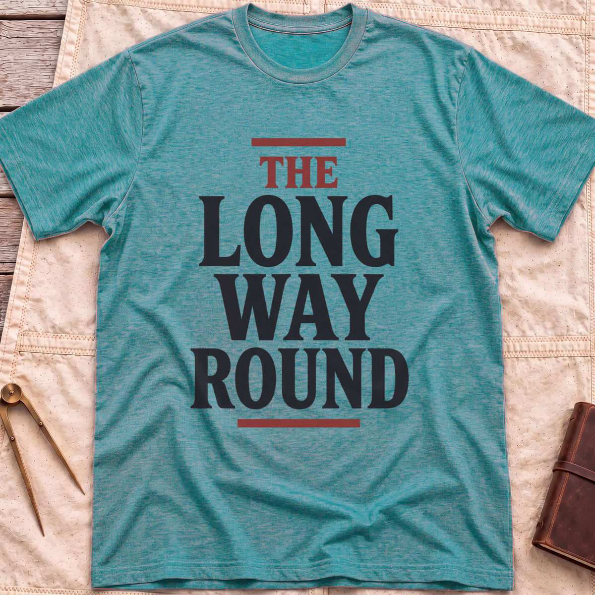 Front view of the heather galapagos blue The Long Way Round T-Shirt with the words The Long Way Round in heavy serif capitals between red rules.