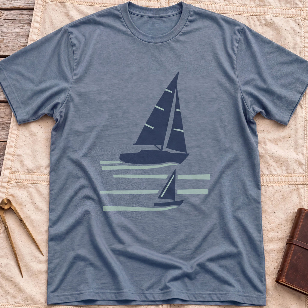 Front view of the heather indigo Two Wake T-Shirt with a large and a small sailboat over pale wake lines.