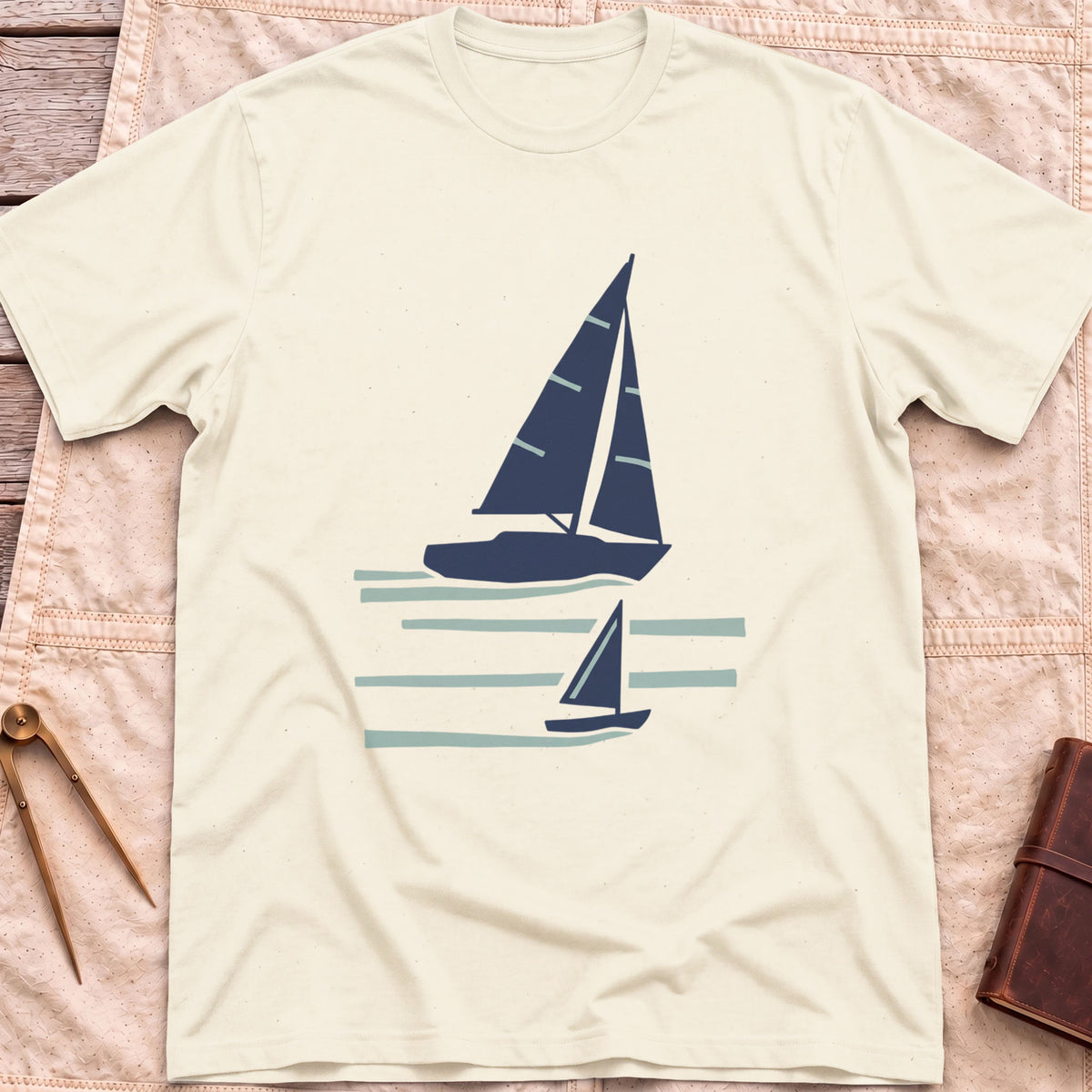 Front view of the natural Two Wake T-Shirt with a large and a small sailboat over pale wake lines.