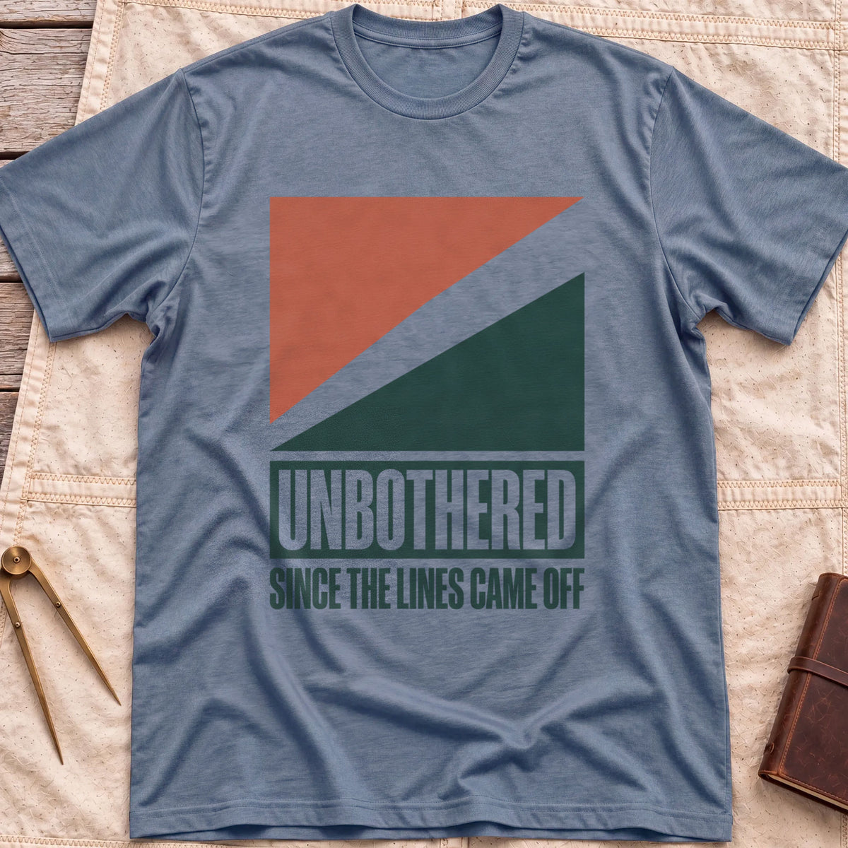 Front view of the heather indigo Unbothered T-Shirt with rust-red and dark green diagonal blocks above the words Unbothered, Since the Lines Came Off.