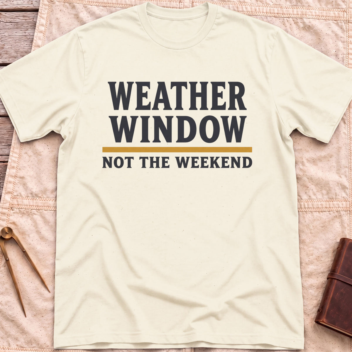Front view of the natural Weather Window T-Shirt with the words Weather Window above a tan rule and Not the Weekend.