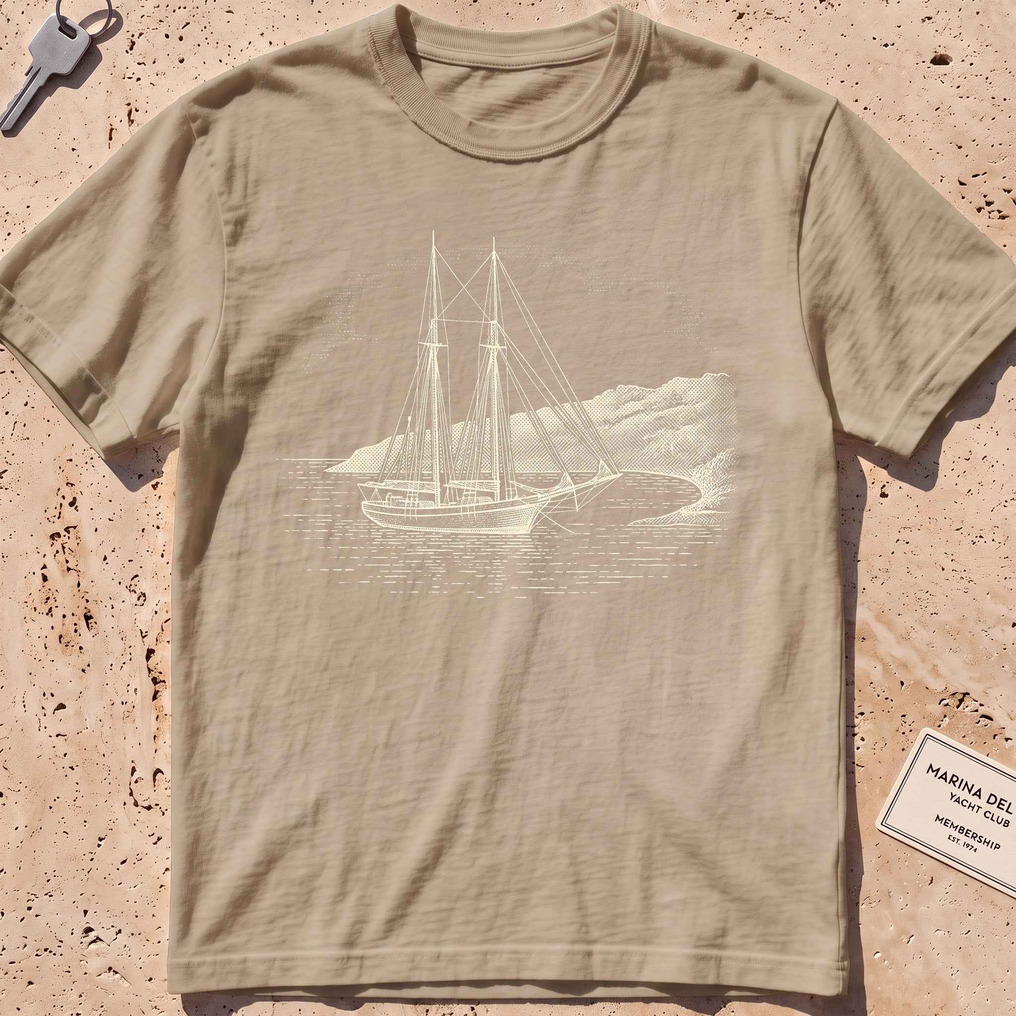 khaki heavyweight tee with an etched schooner moored in a cove graphic.