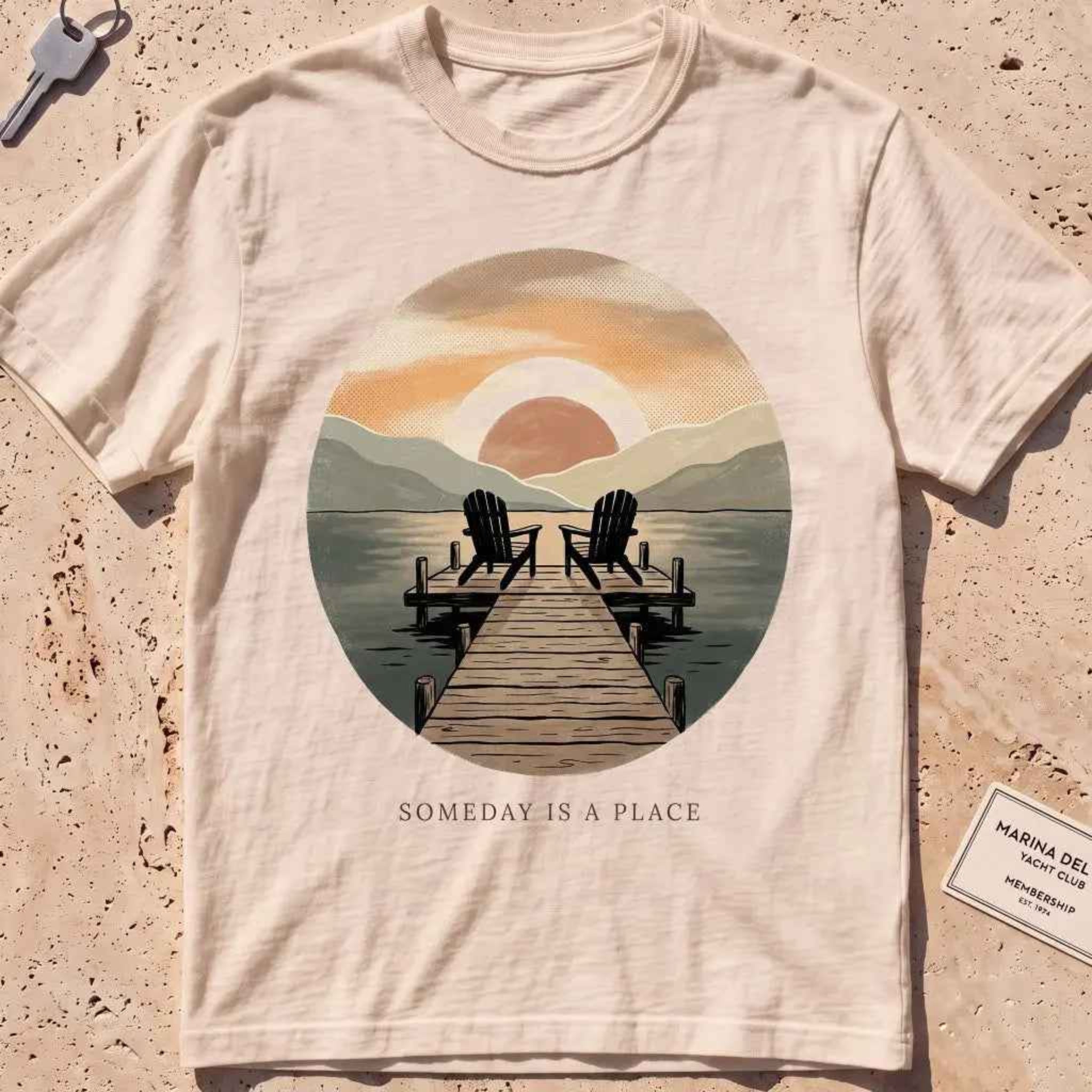 ivory heavyweight tee with a warm dock-at-dusk "Someday Is a Place" scene.