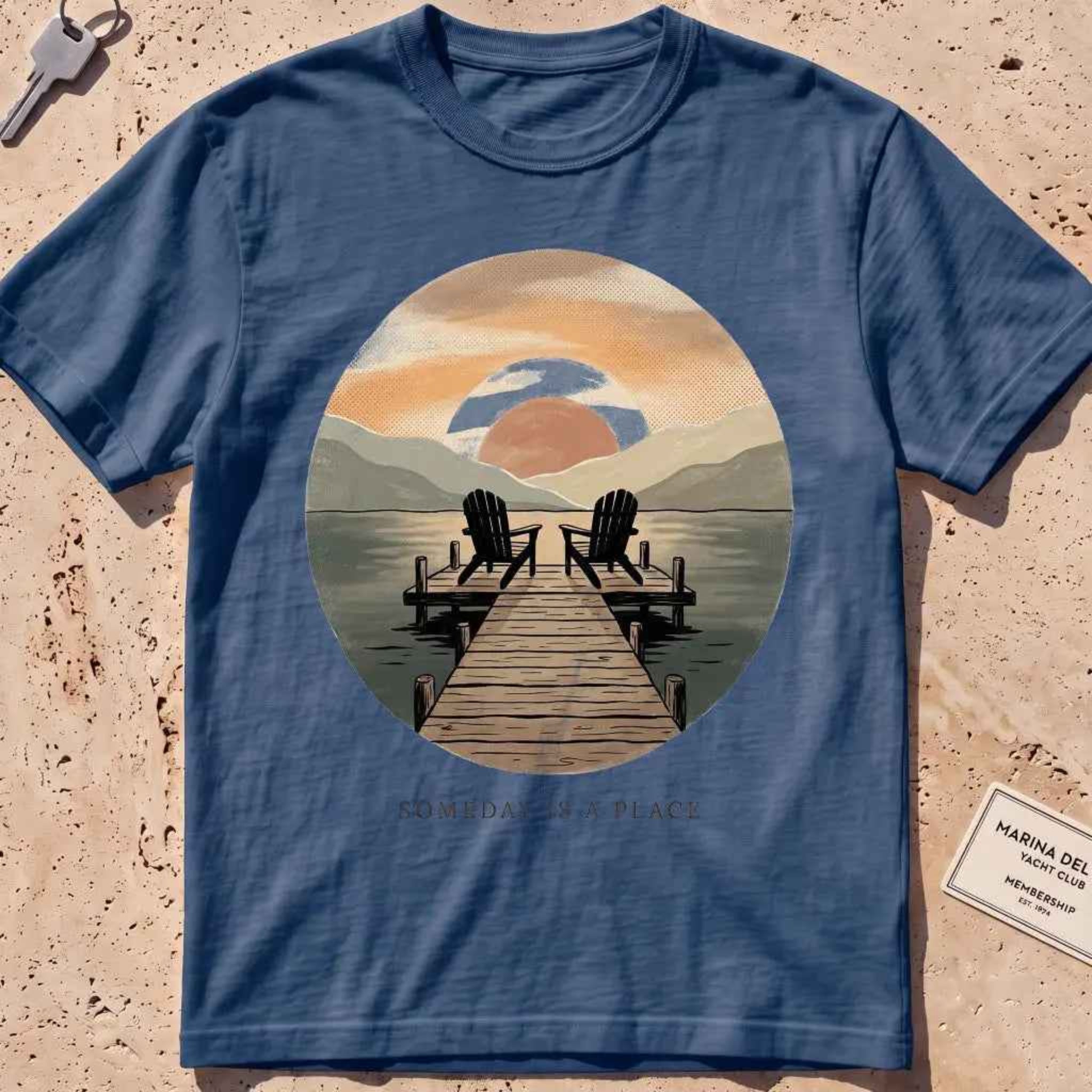 midnight heavyweight tee with a warm dock-at-dusk "Someday Is a Place" scene.